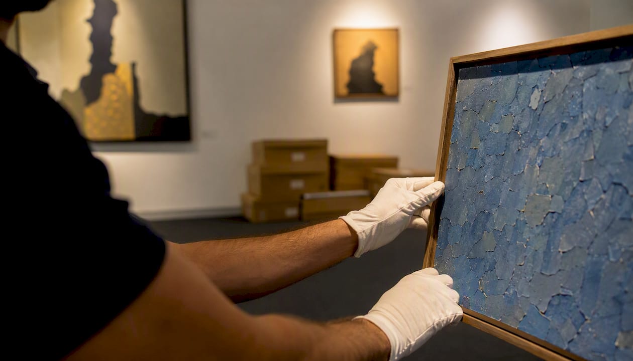 Collector inspecting framed blue chip artwork