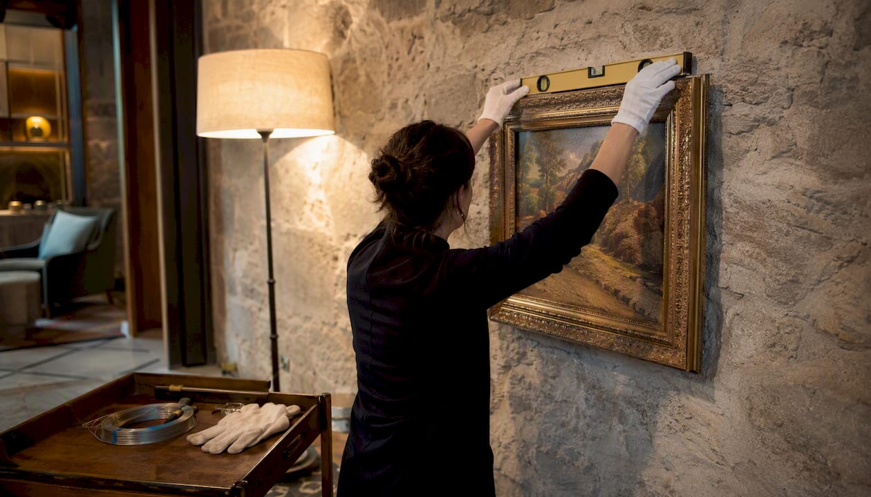 Conservator installing framed artwork in hotel lobby