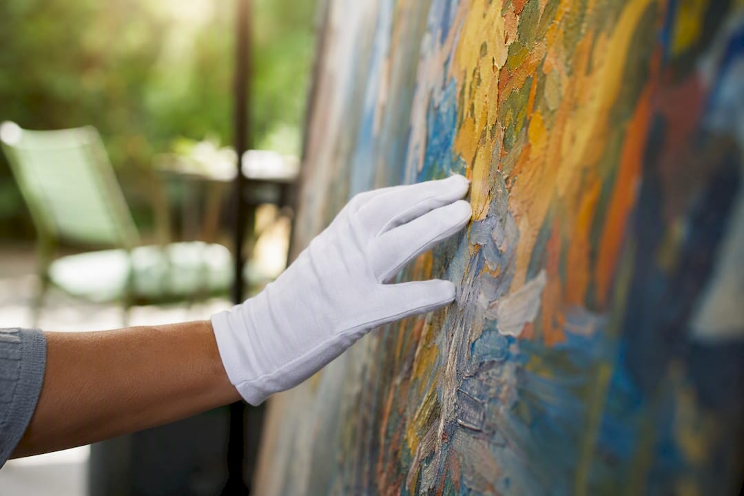 Gloved hand inspecting artwork condition