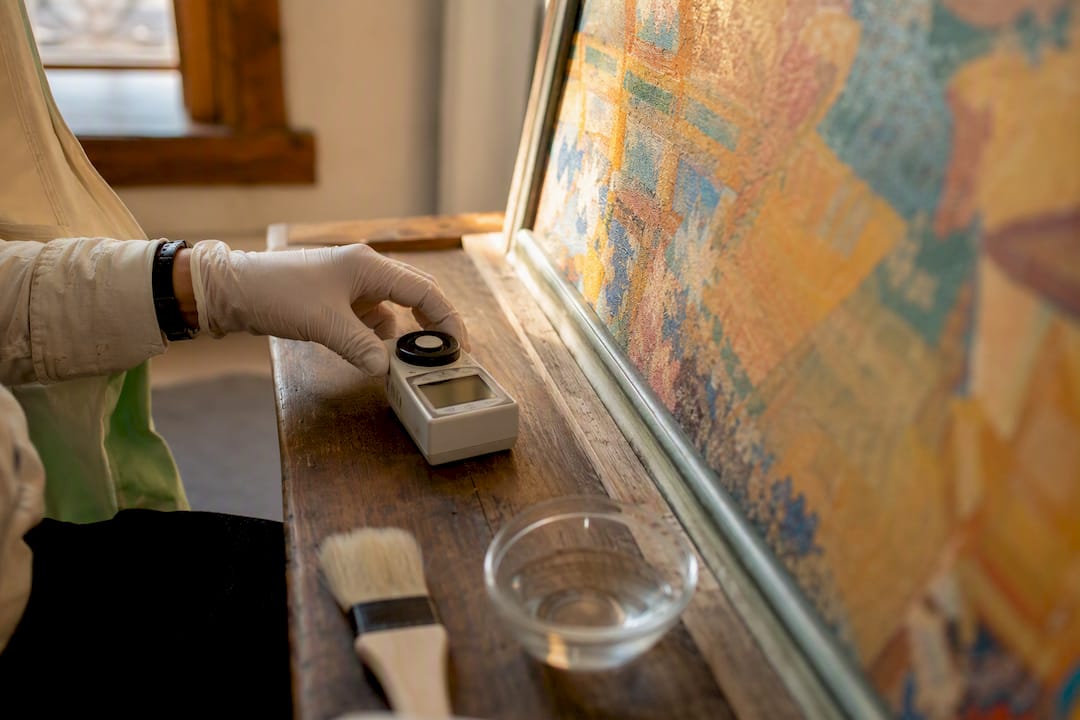 Gloved hand measuring humidity near artwork