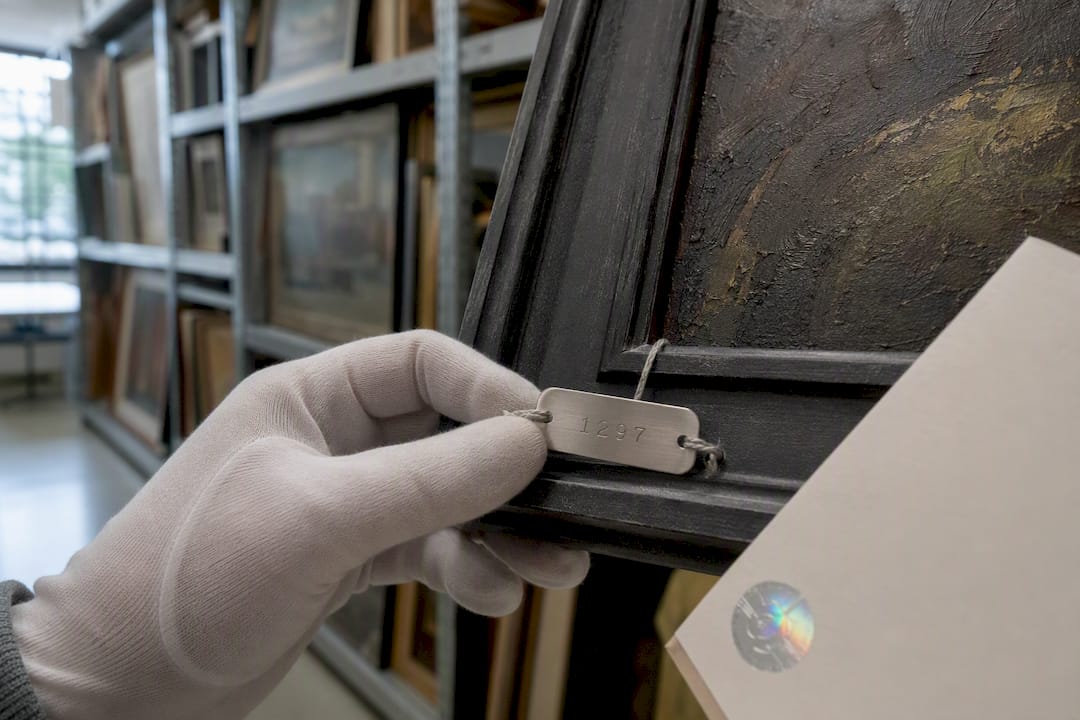 Gloved hand showing serial number tag on artwork frame