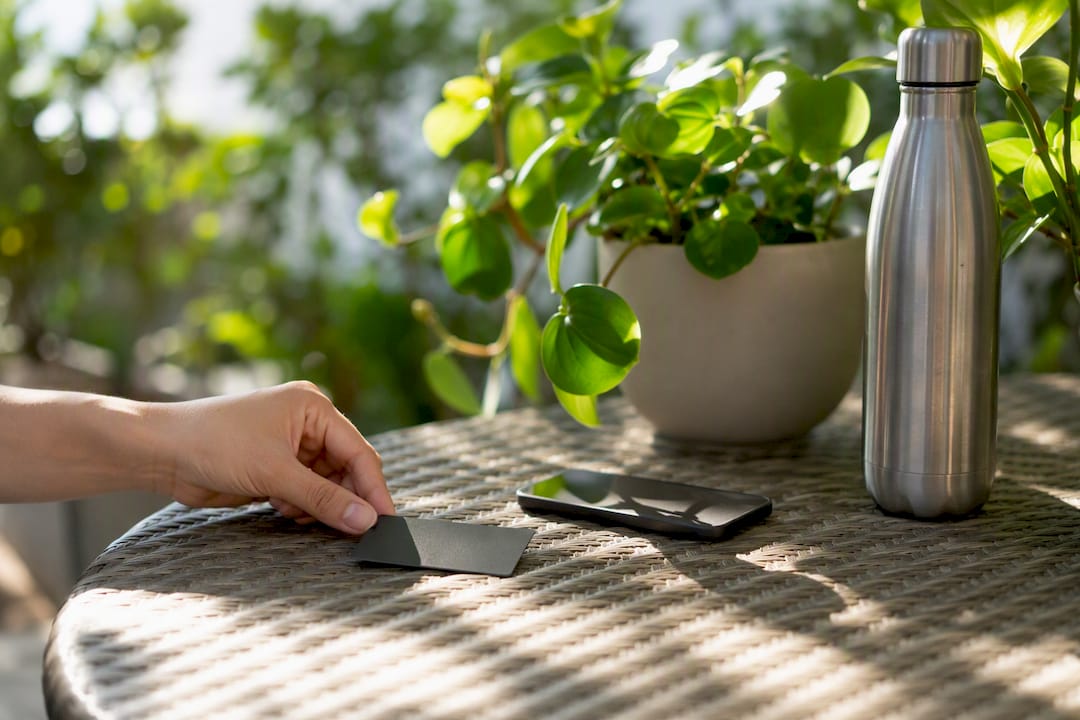 Hand placing credit card near smartphone on table