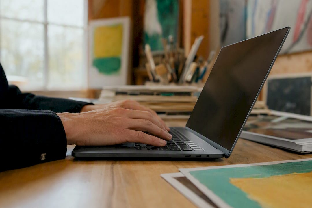 Hands typing artwork file names on laptop keyboard