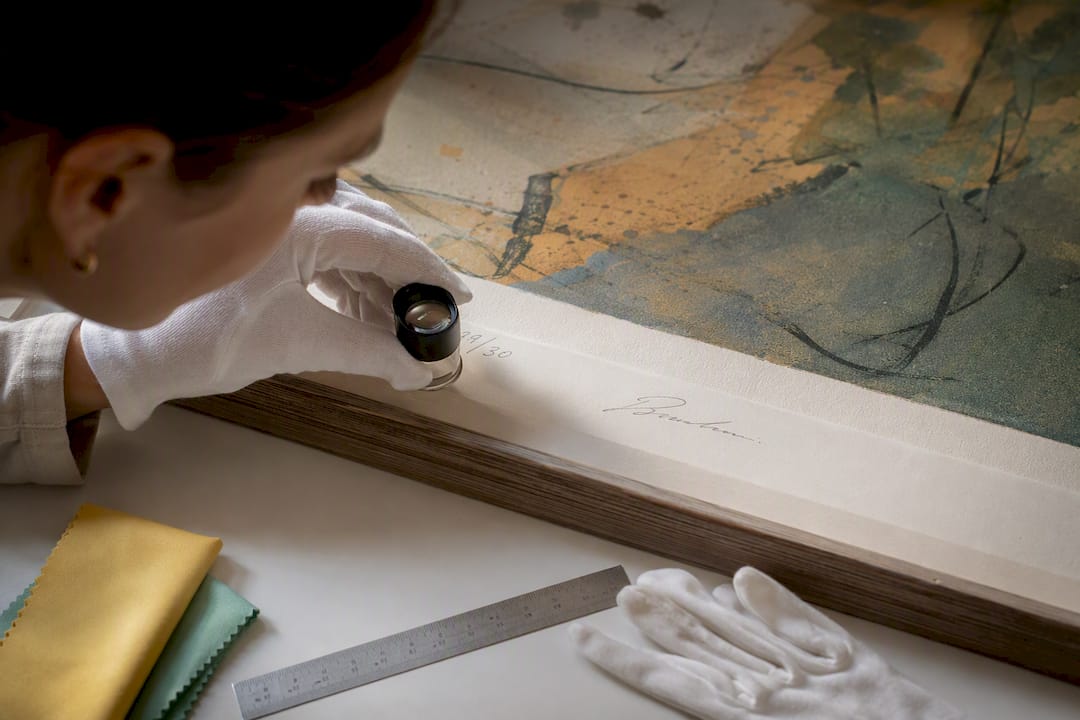 Conservator inspecting artwork signature