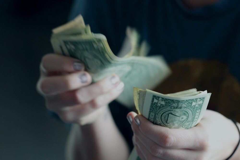 focus photography of person counting dollar banknotes
